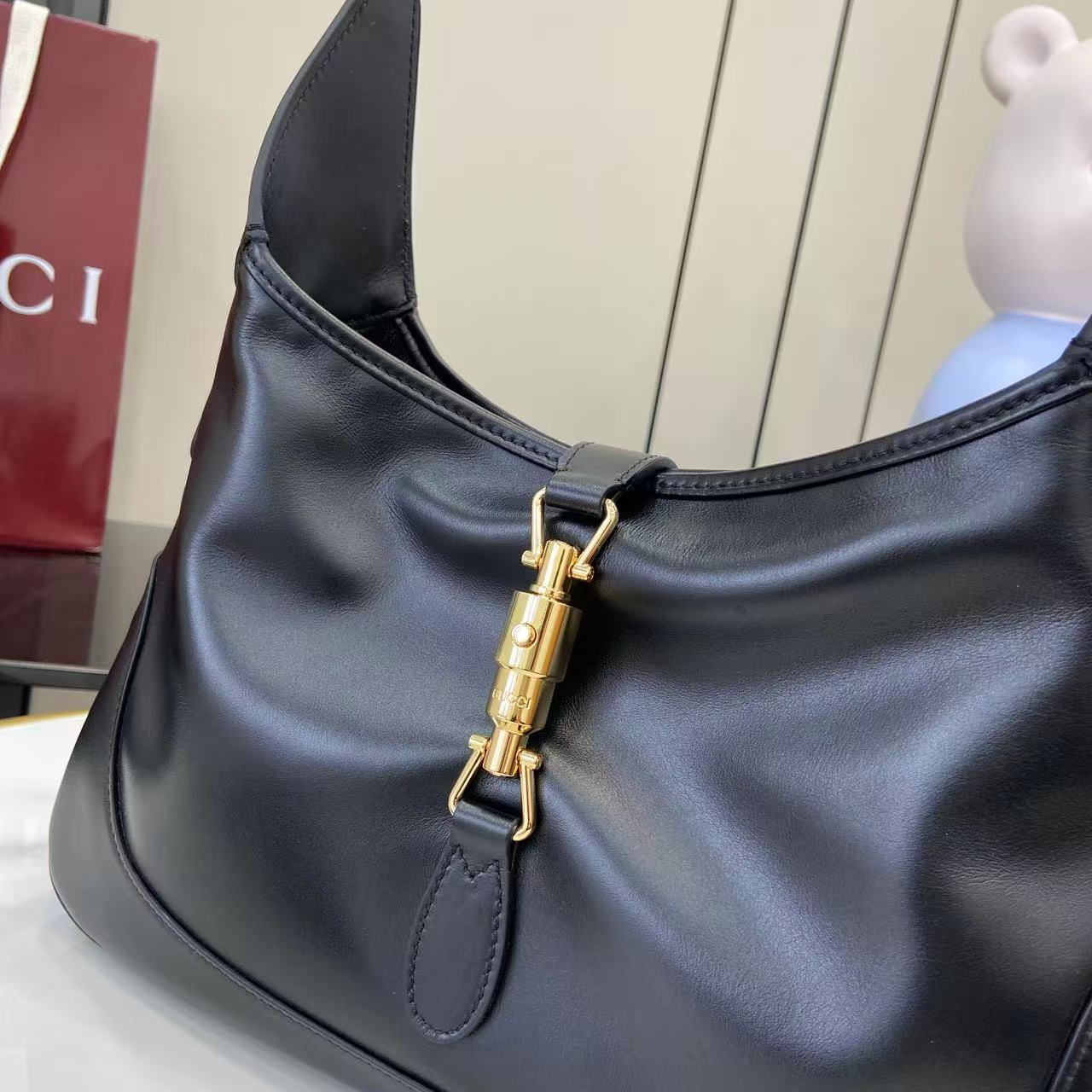 Black leather hobo bag front detail with gold-tone clasp and stitched accent panel