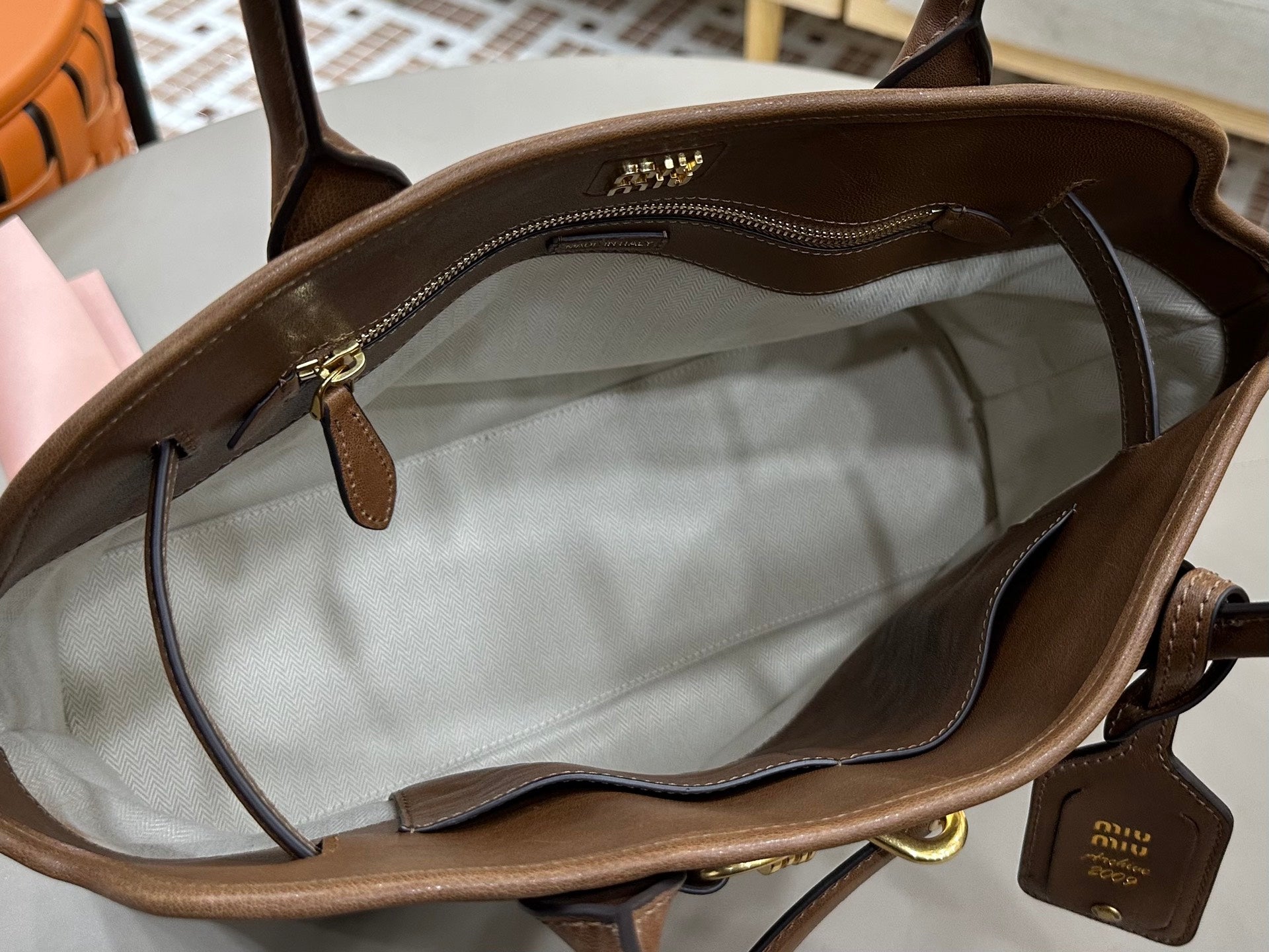 Brown leather handbag interior opening with zip pocket and leather trim