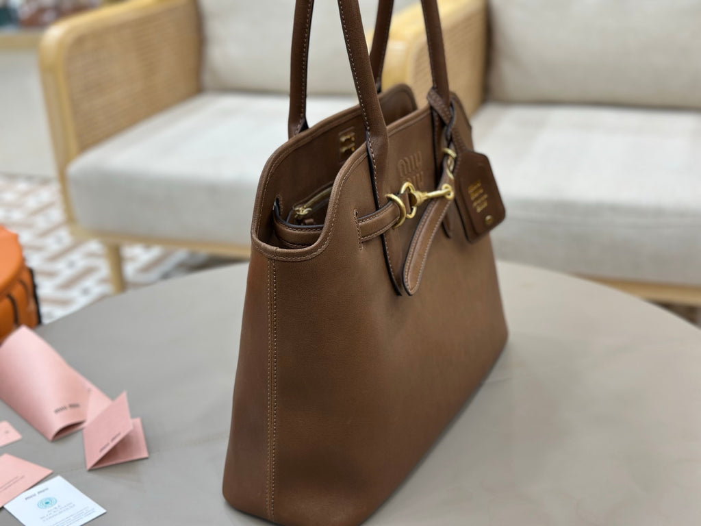 Brown leather handbag side view with top handles and hanging luggage tag