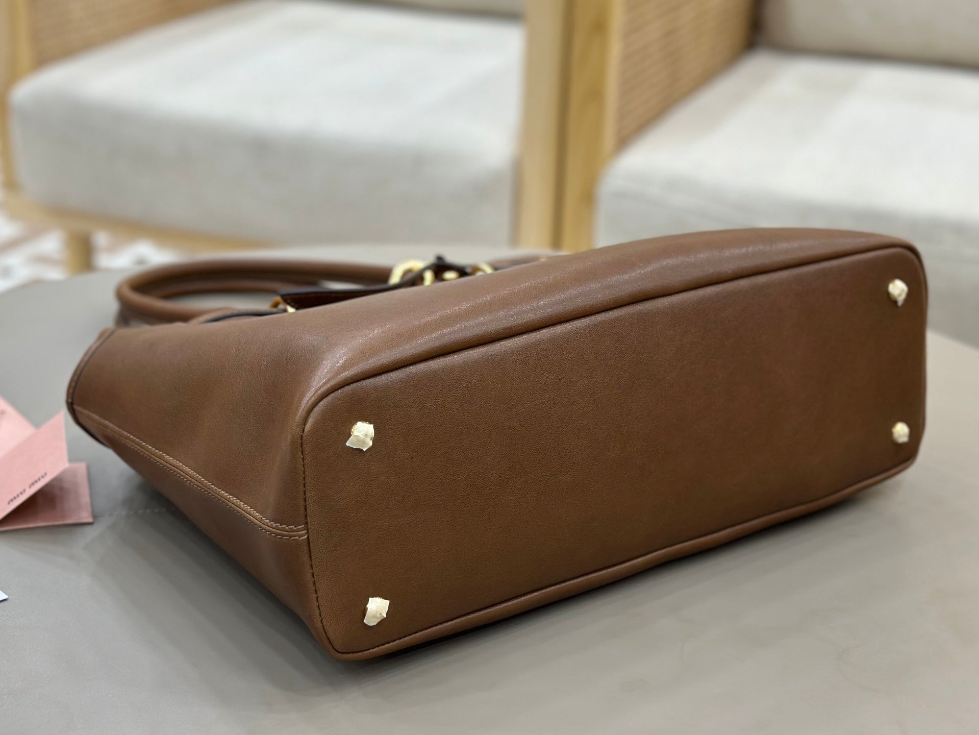 Brown leather handbag with visible base and gold-toned corner feet