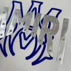 White Amiri sweatshirt graphic close-up with blue lettering and shiny silver metal details
