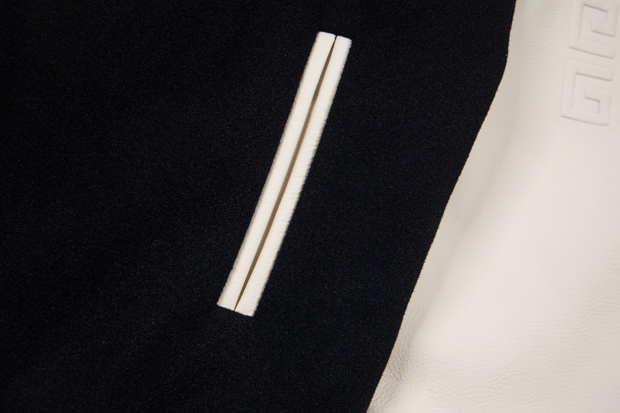 Black varsity jacket with cream sleeve panel and vertical striped detail