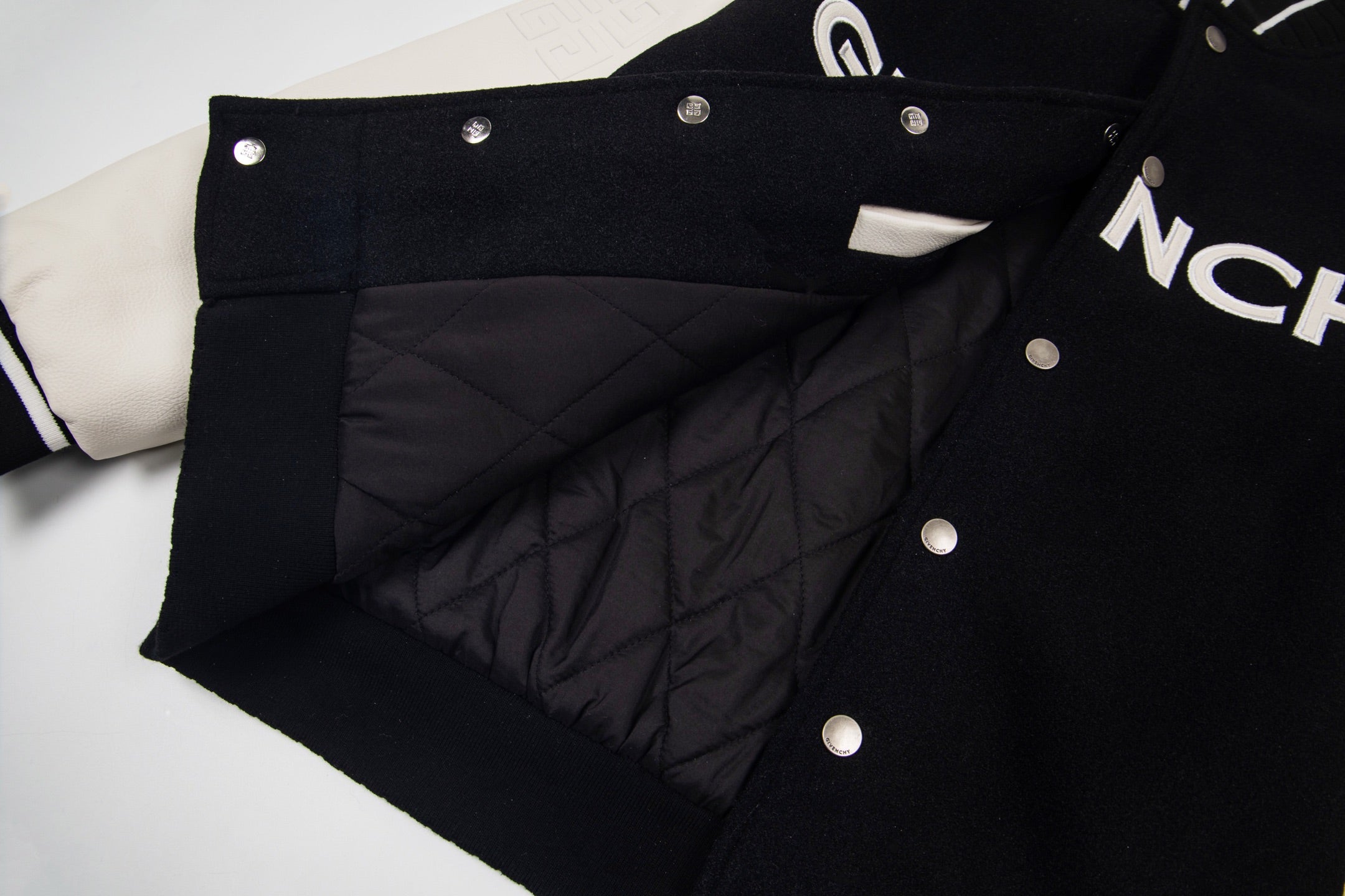 Black varsity jacket with quilted lining panel and metal snap buttons