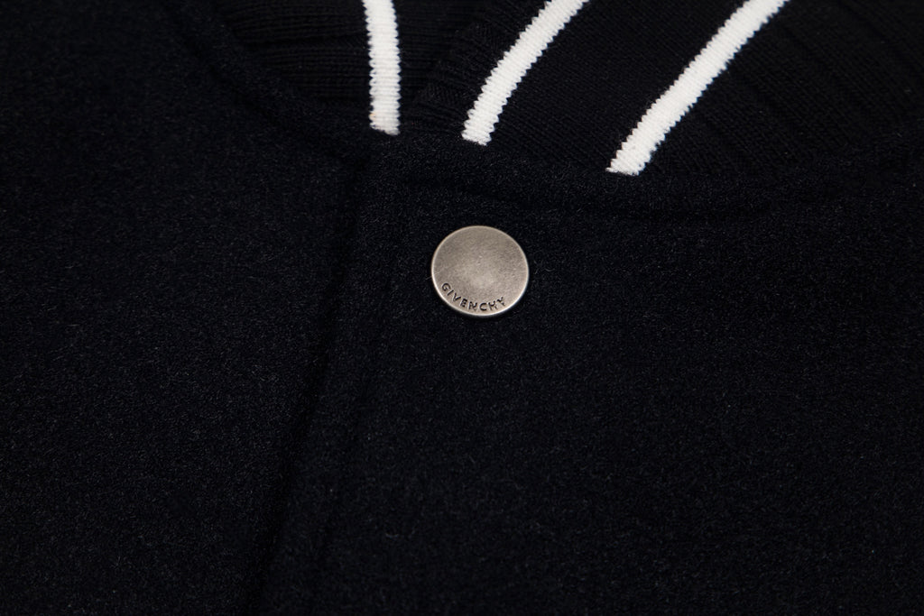 Black varsity jacket front with round metal snap button and striped trim