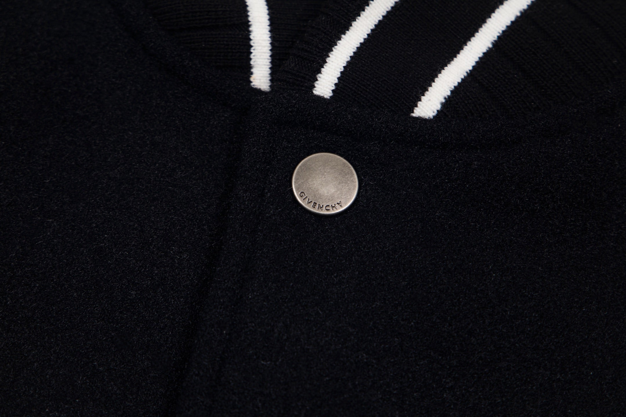 Black varsity jacket front with round metal snap button and striped trim
