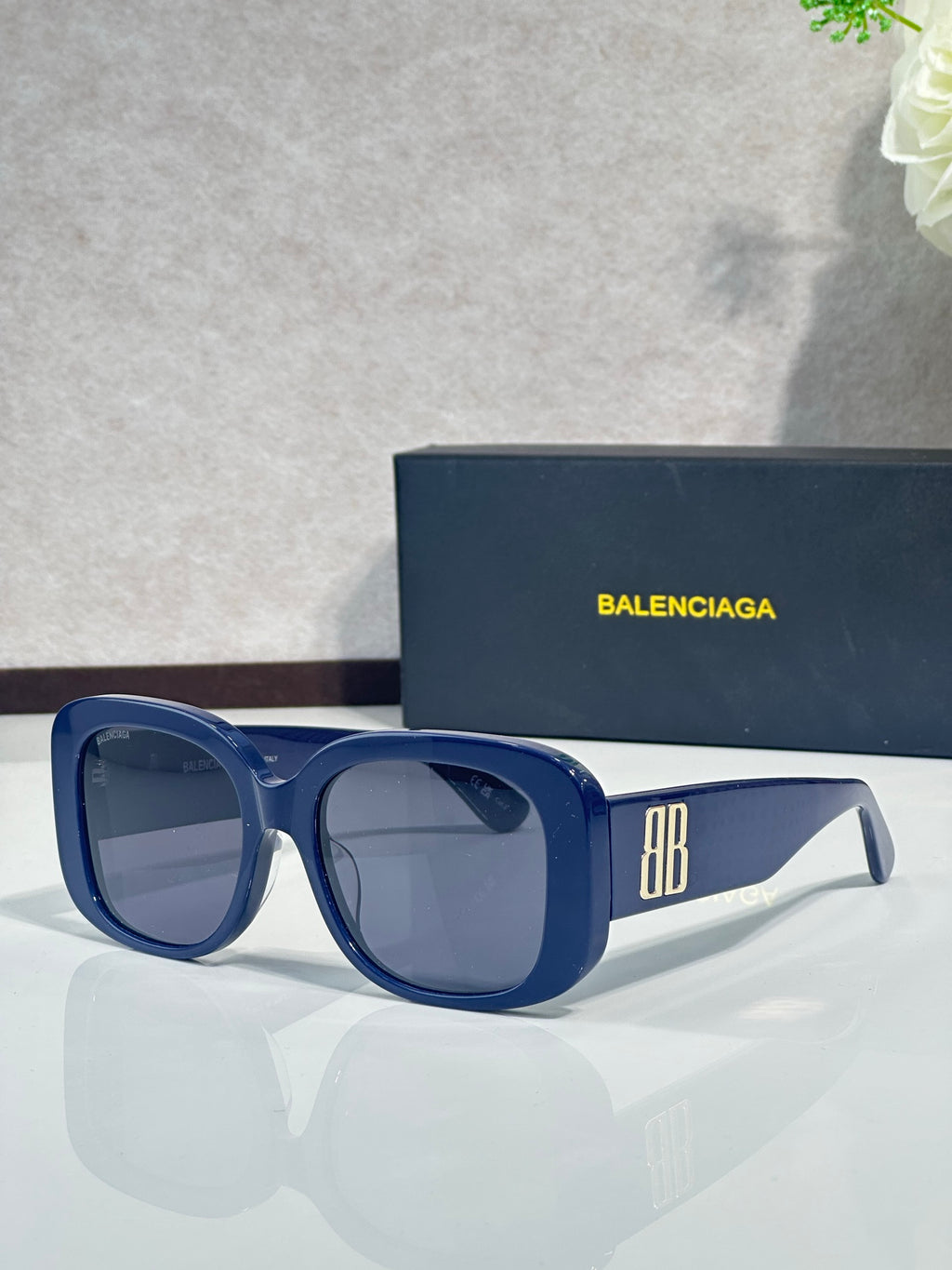 Blue sunglasses with square frames, dark lenses, and BB logo on the side