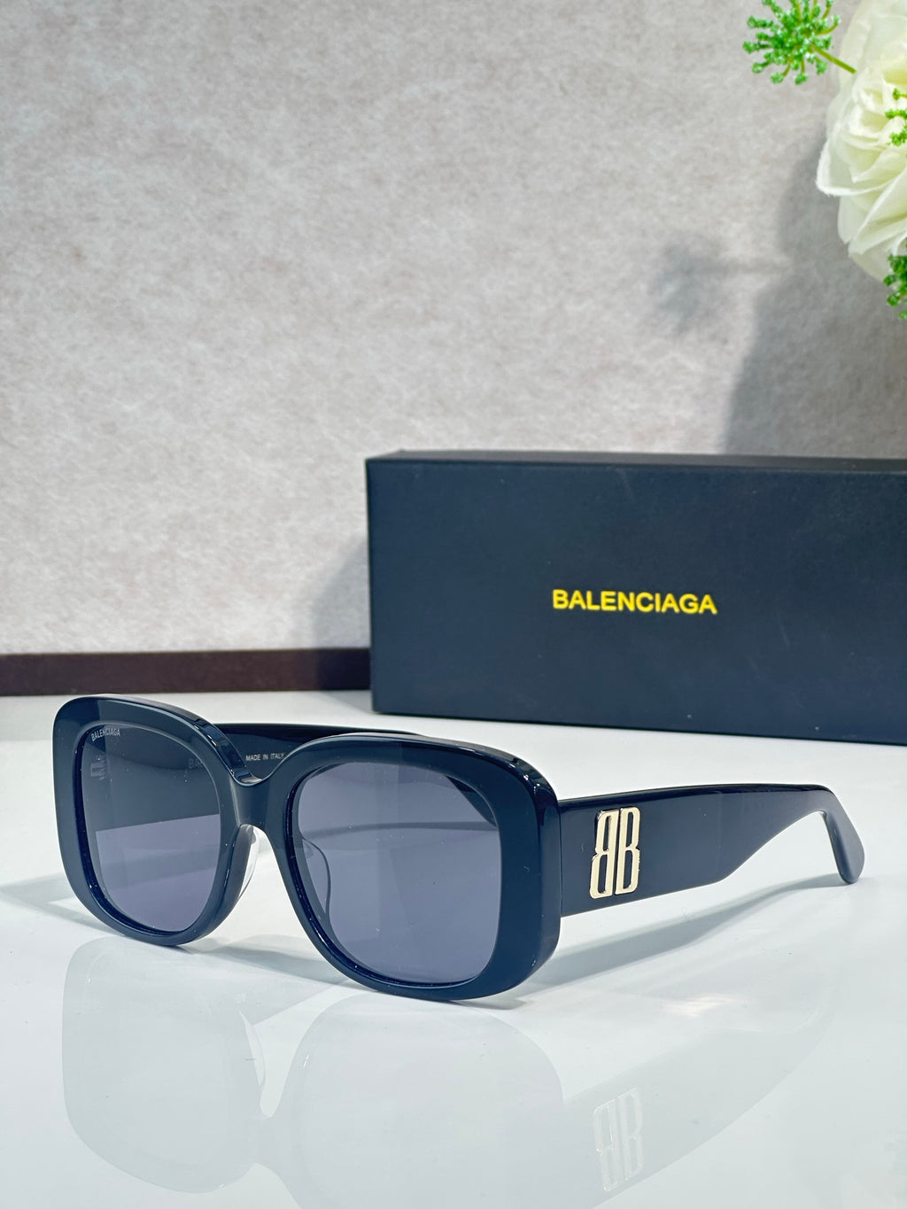 Blue sunglasses with rounded-square frames, dark lenses, and BB logo on the arm
