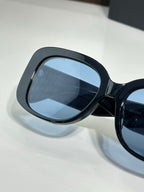 Sunglasses close-up with dark frame, blue lens, and BB logo arm detail
