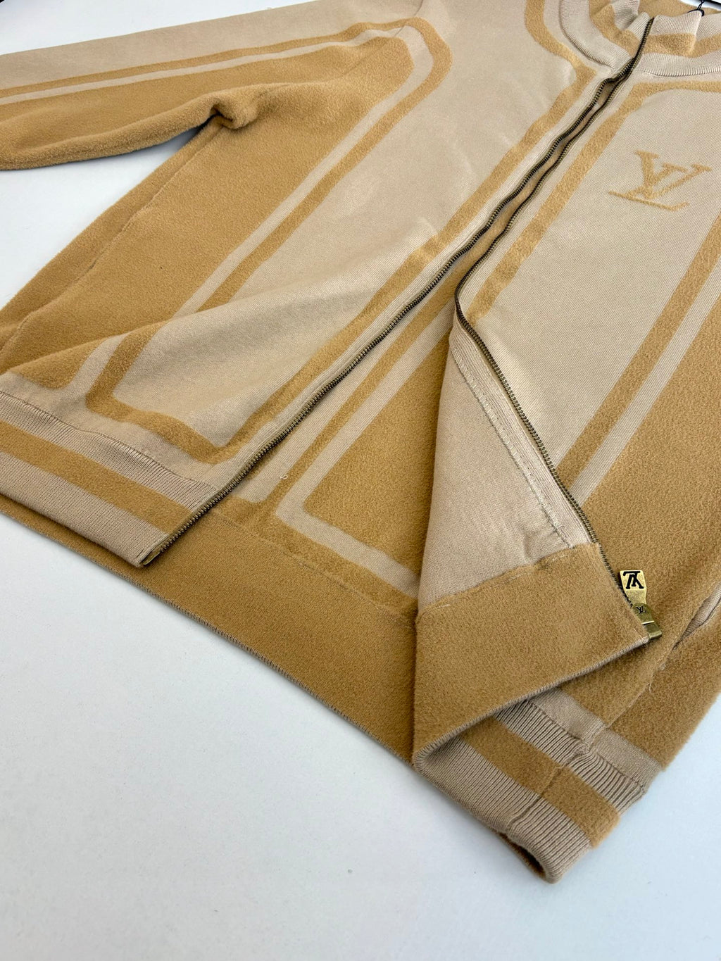 Beige knit zip jacket folded showing zipper tape and striped trim