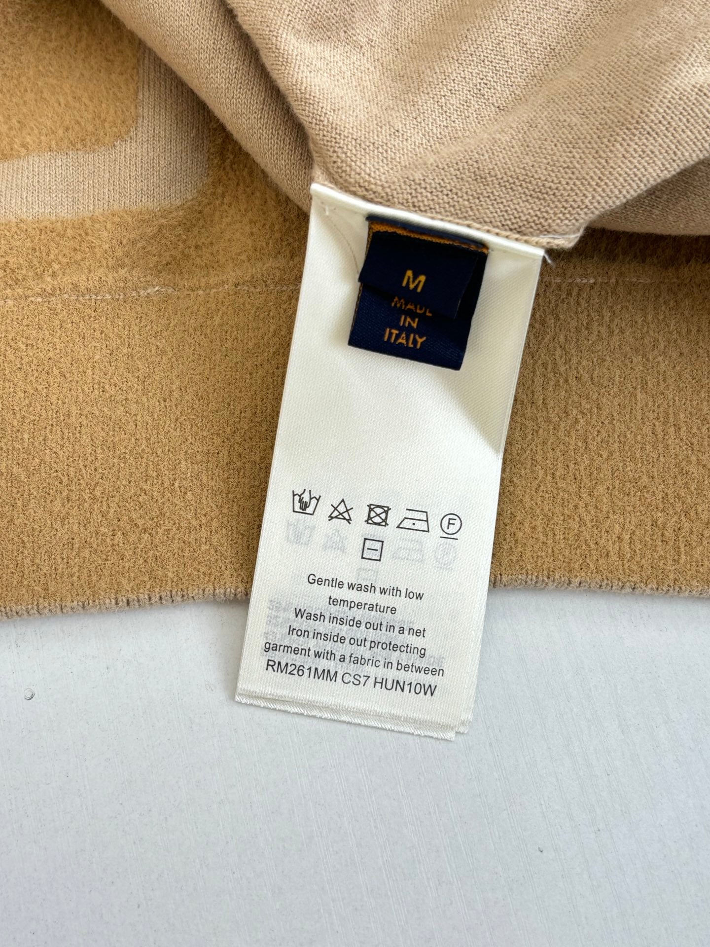 Long knit sweater care label with size M and washing symbols