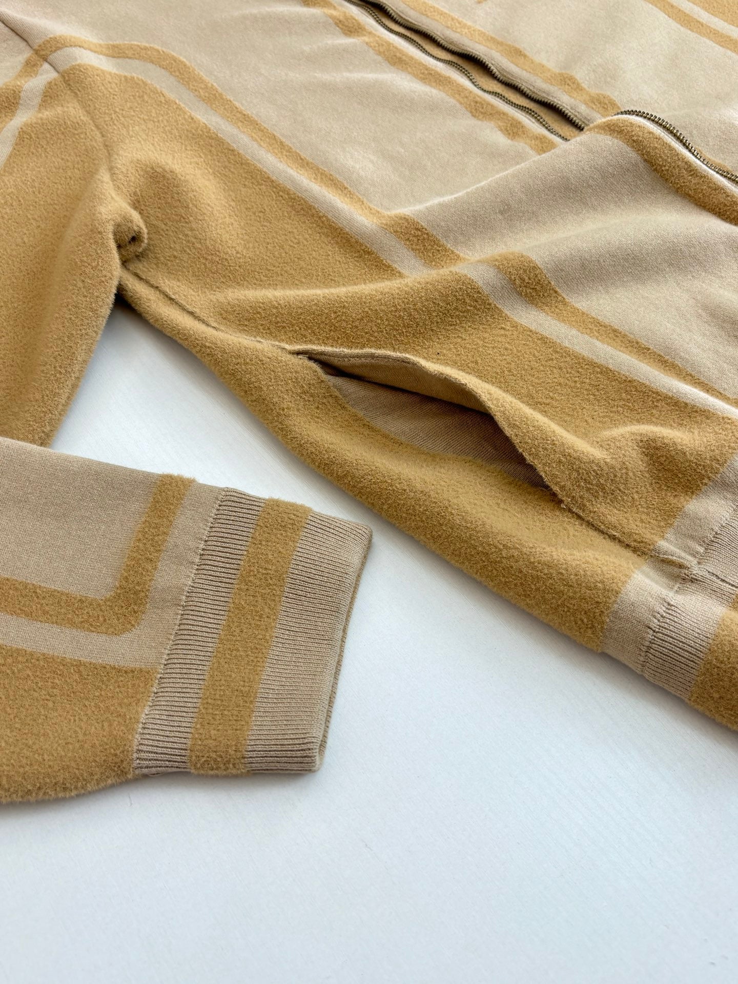 Beige knit sleeve with gold stripe motif and ribbed cuff
