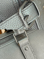 Metal zipper pull and rivet hardware on dark teal textured leather duffel bag