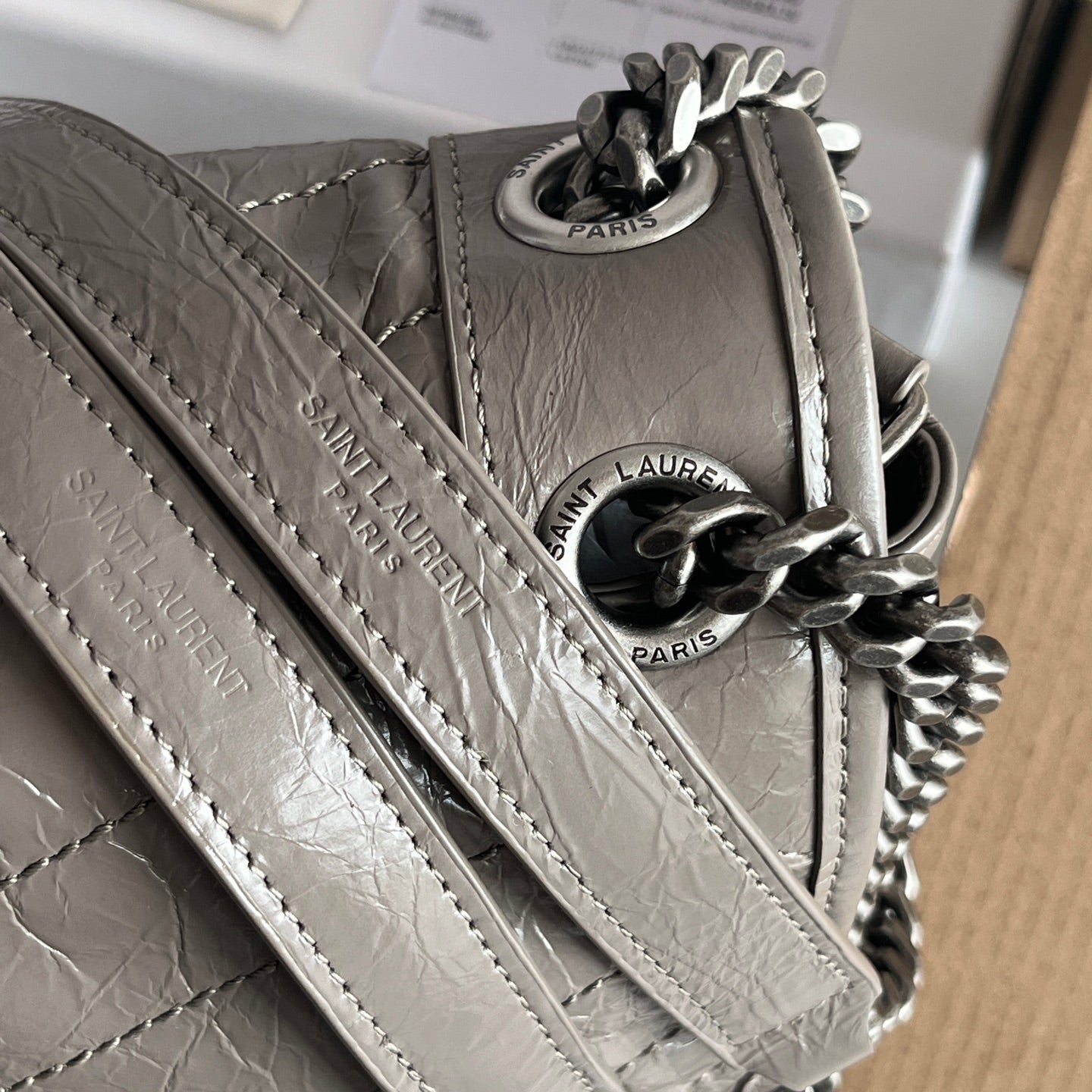 Silver leather shoulder bag close-up of strap and chain links with Paris tags