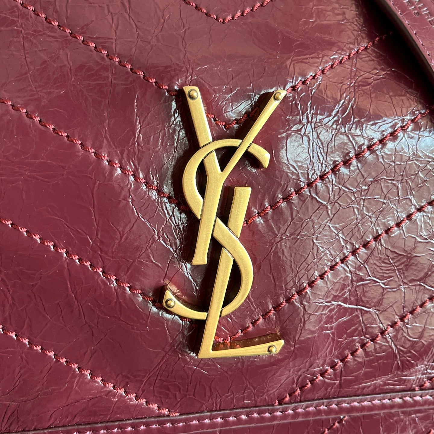 Saint Laurent YSL logo on burgundy quilted leather flap with gold hardware