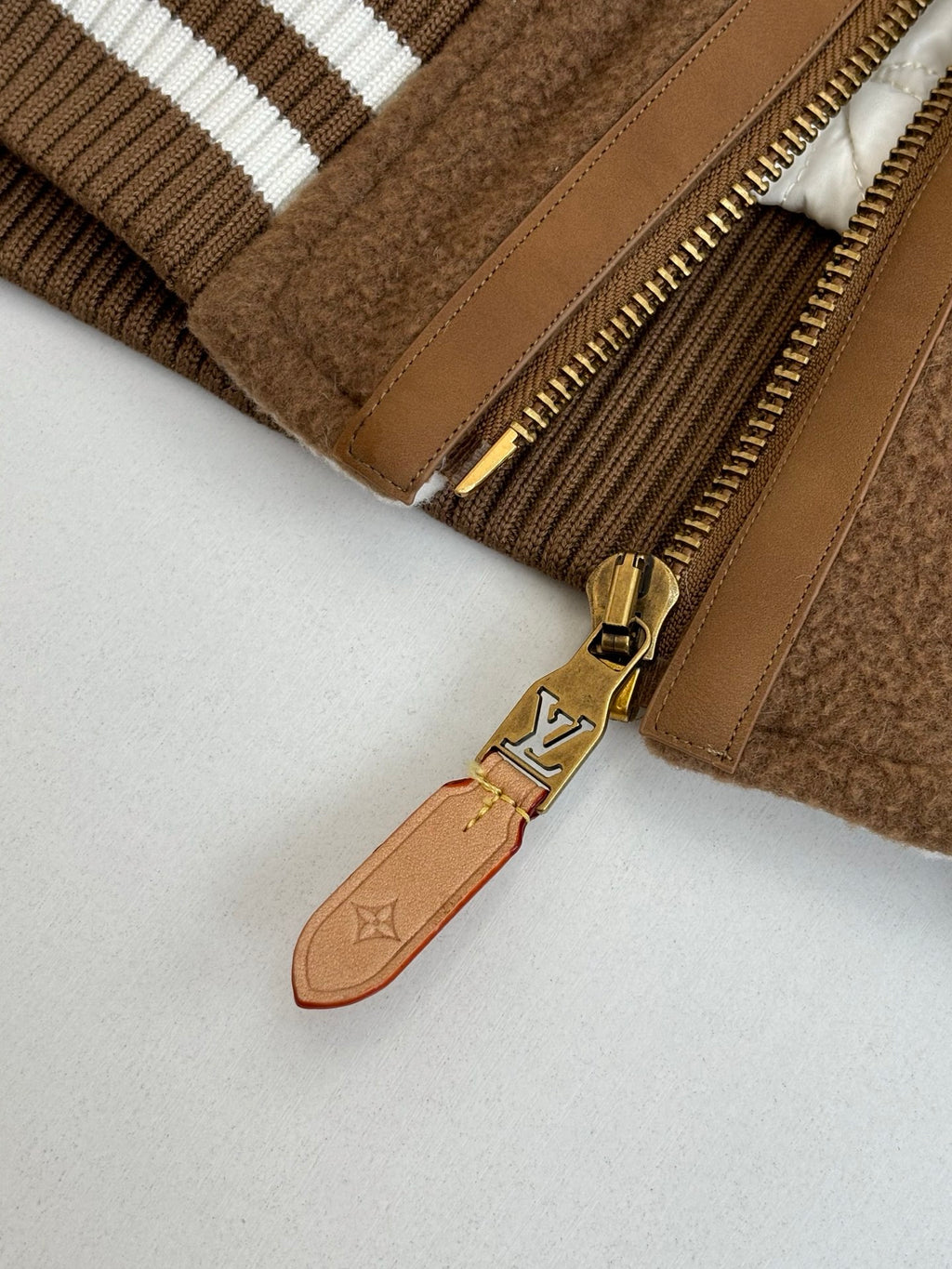 Louis Vuitton long jacket close-up of brass zipper and LV charm pull