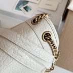 YSL bag side view with white textured leather, gold-tone chain strap, logo emblem