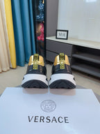 Black sneakers with gold heel accents, rear styling details and chunky white sole.