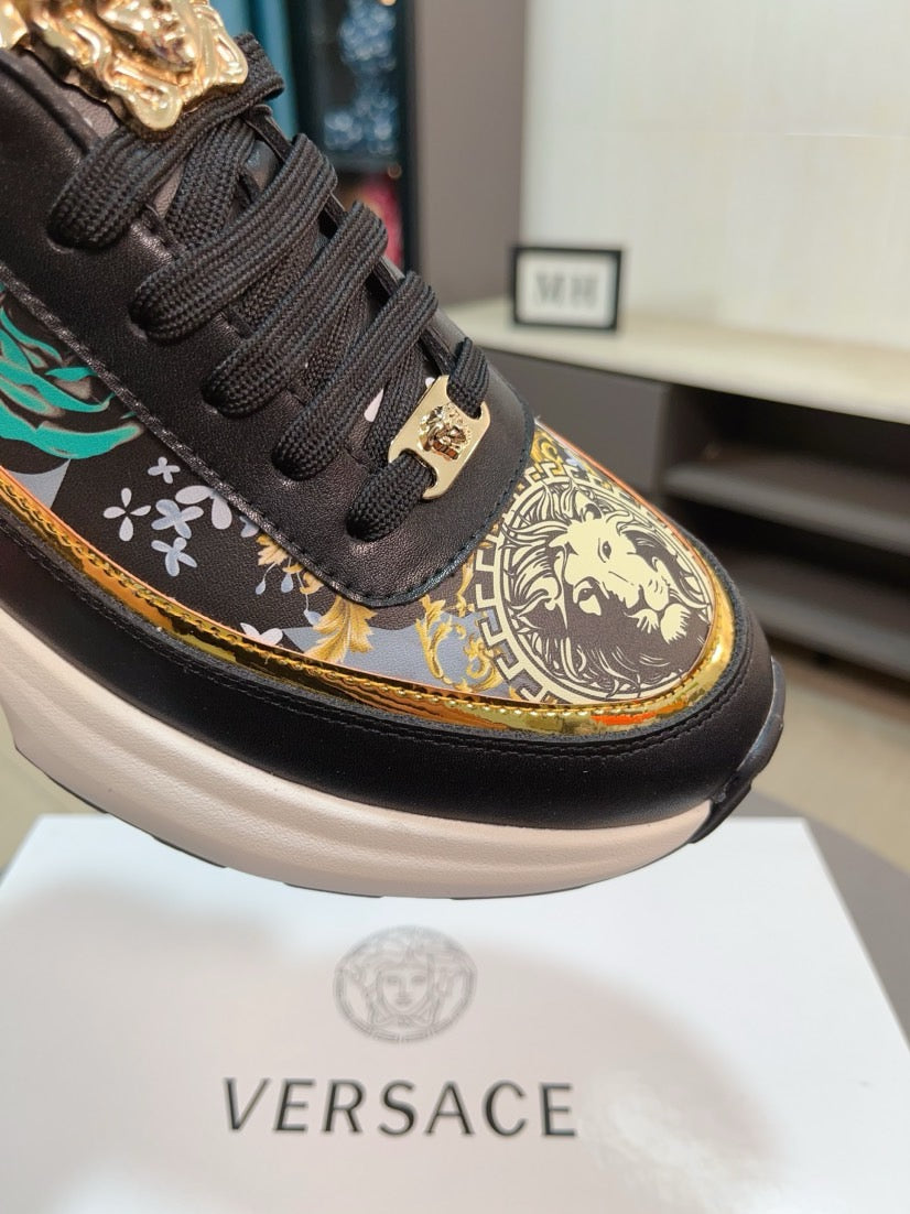 Black sneaker toe with gold emblem and patterned detail; lace-up and thick white sole.