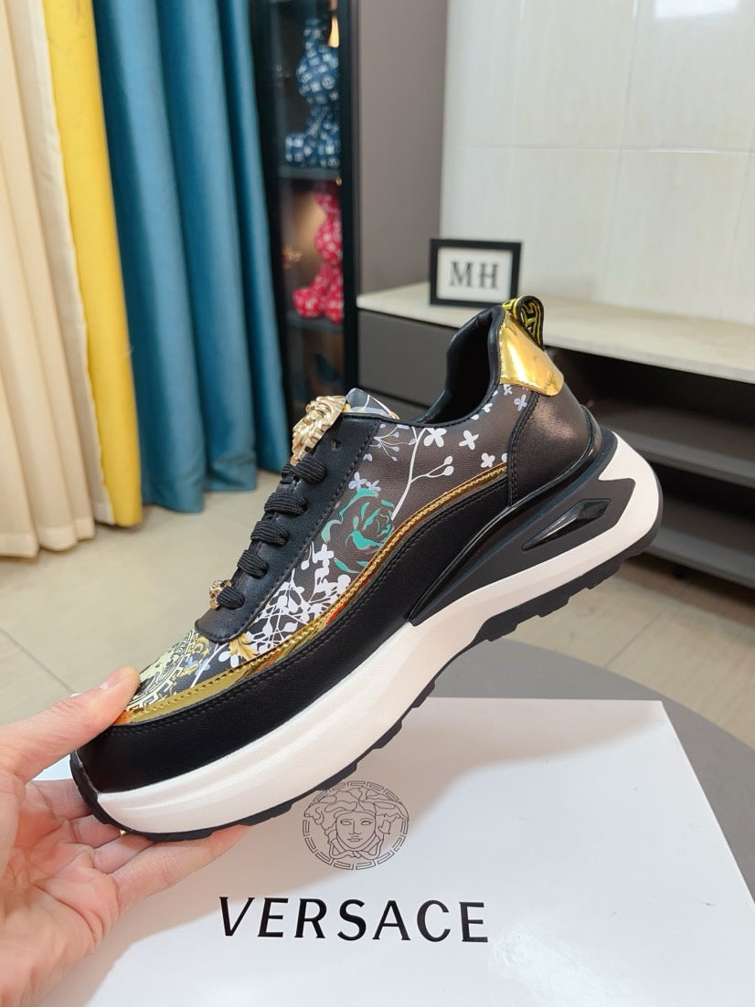 Black sneakers with gold-trimmed patterned upper, lace-up closure and thick white sole.