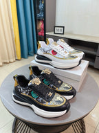Black sneakers with gold trim, patterned uppers, lace-up front and chunky white sole.