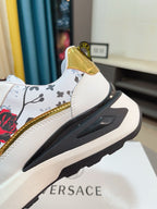 Versace sneaker heel side detail with white upper, gold trim, and sculpted rubber sole