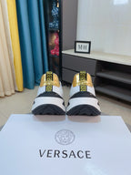 Versace sneakers pair with white uppers and gold logo heel accents, lace-up style