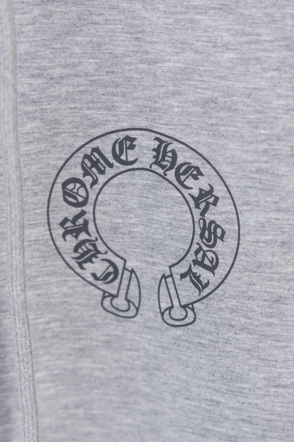 Grey hoodie fabric with circular logo graphic on the front.