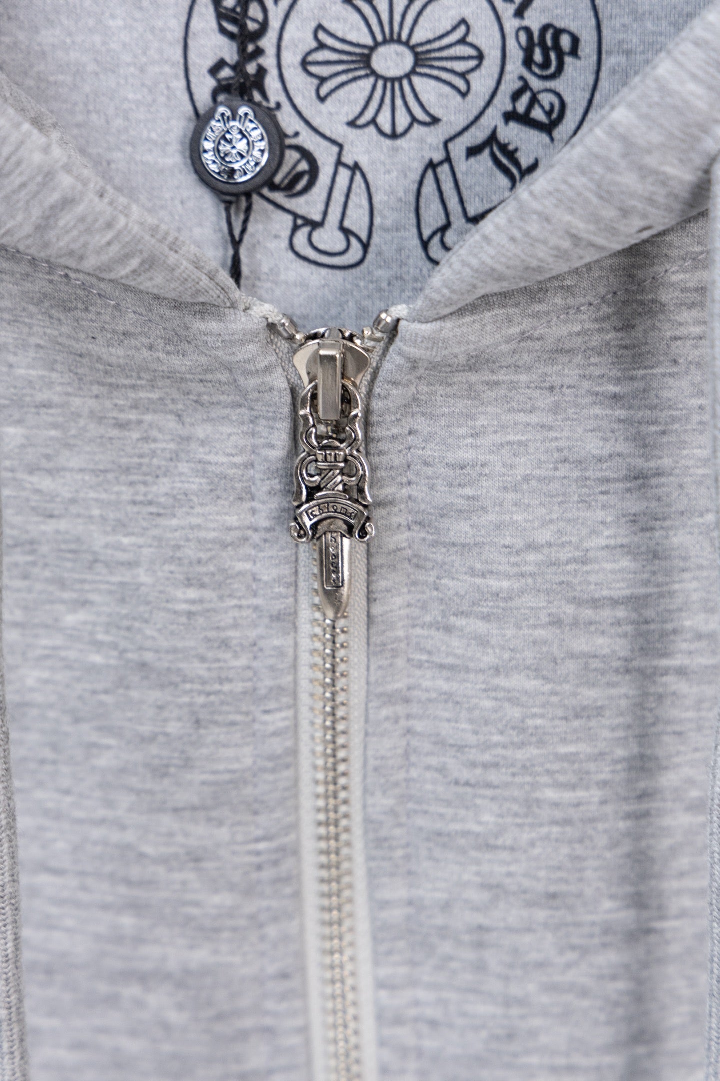 Grey zip hoodie with metal zipper and large chest logo graphic.