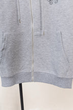 Grey zip hoodie hem with front pocket openings and centered zipper.