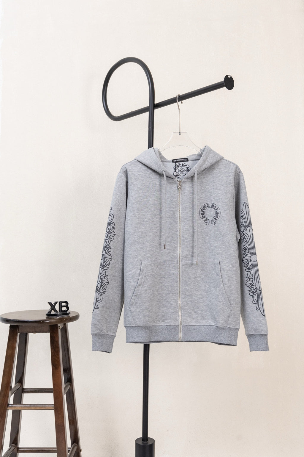 Grey long-sleeve zip hoodie with hood, front pockets, and graphic sleeve print.