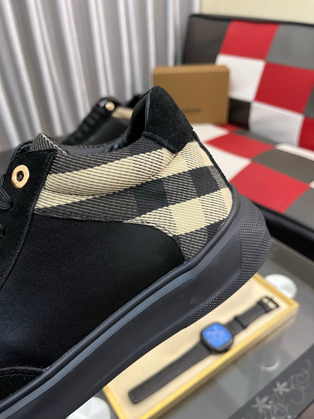 Close-up of black low-top sneaker with beige-and-black check trim on side
