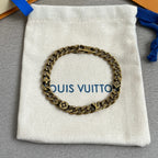 Gold-tone chain bracelet on white drawstring pouch, monogram charms