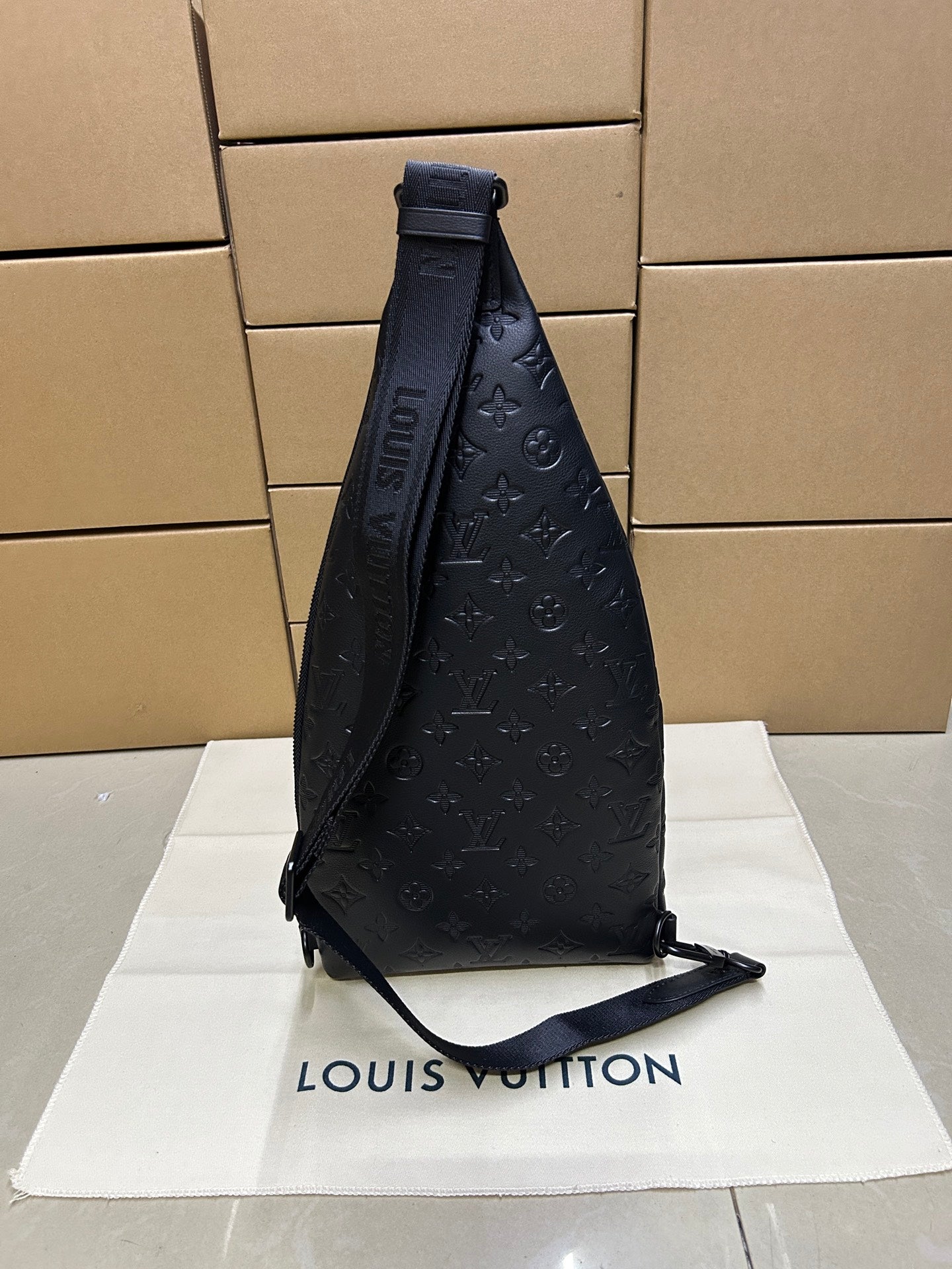 Men's Louis Vuitton monogram leather sling bag, dark blue/black, side view with strap