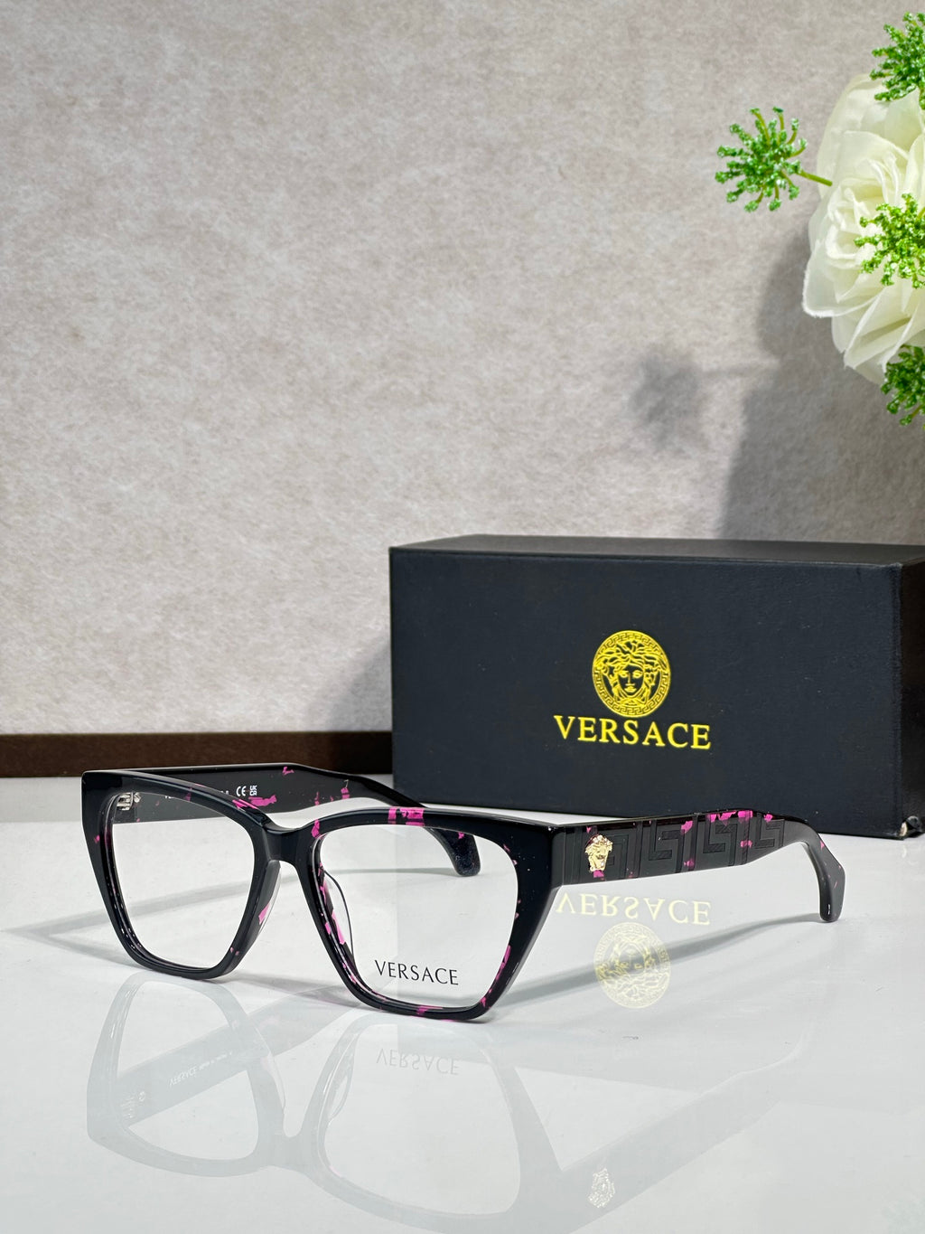 Black eyeglasses with pink patterned temple details, clear lenses, VERSACE logo