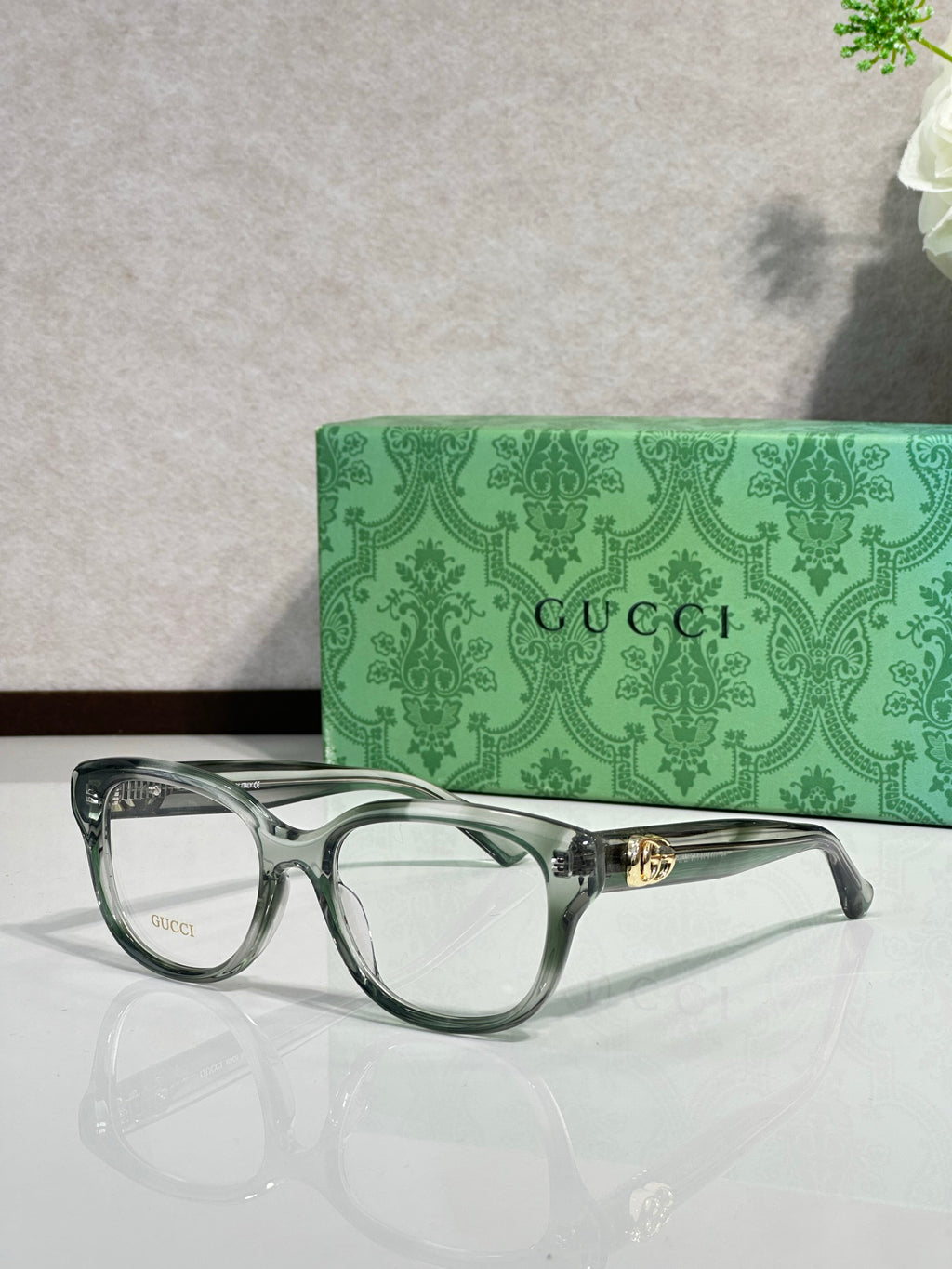 Gucci eyeglasses with clear gray-green frames and gold logo temple detail