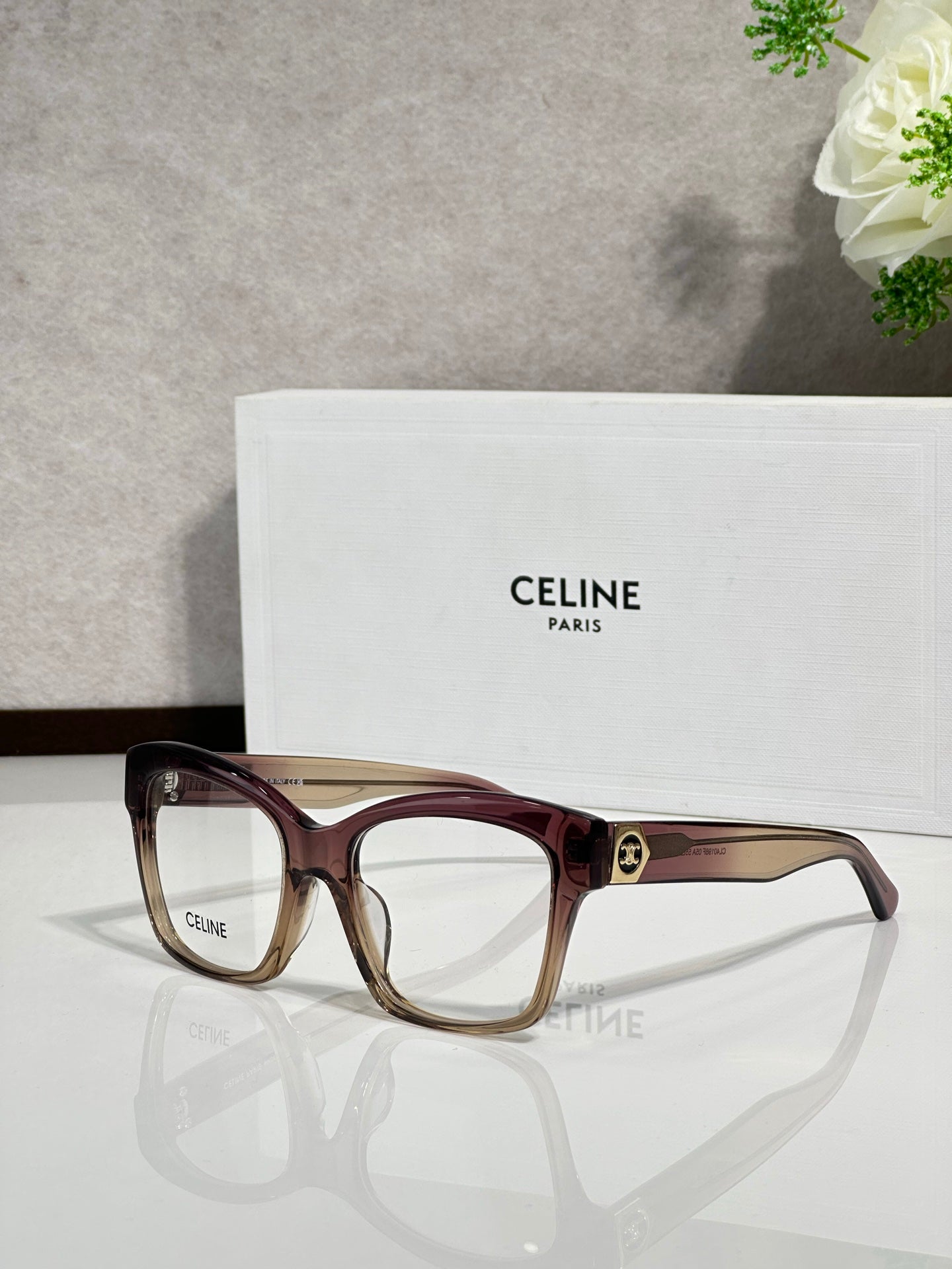 Burgundy eyeglass frames with clear lenses and gold-tone logo at bridge