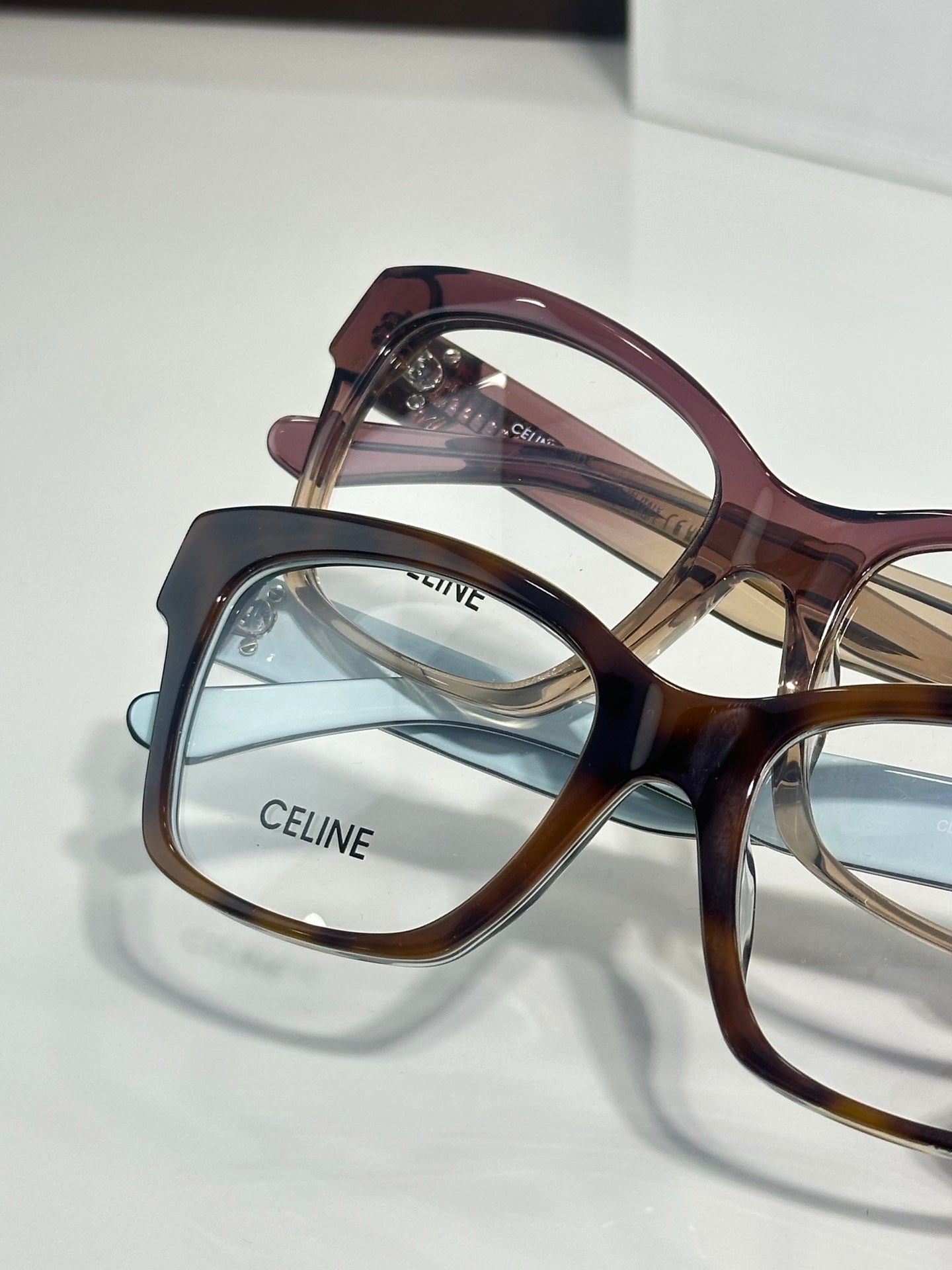 Burgundy and amber eyeglass frames with clear lenses, gold-tone hinge detail