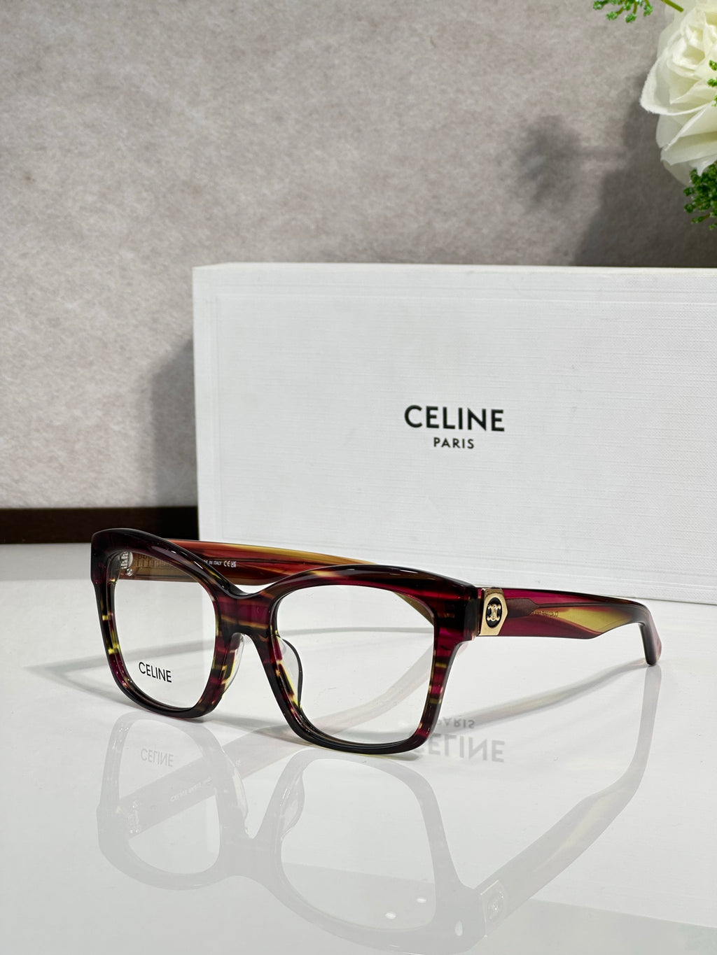 Burgundy eyeglass frames with clear lenses and gold-tone logo at temple