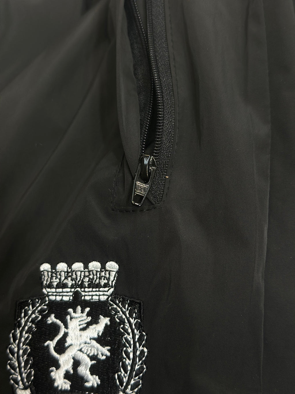 Black pants with front zipper and embroidered lion crest patch