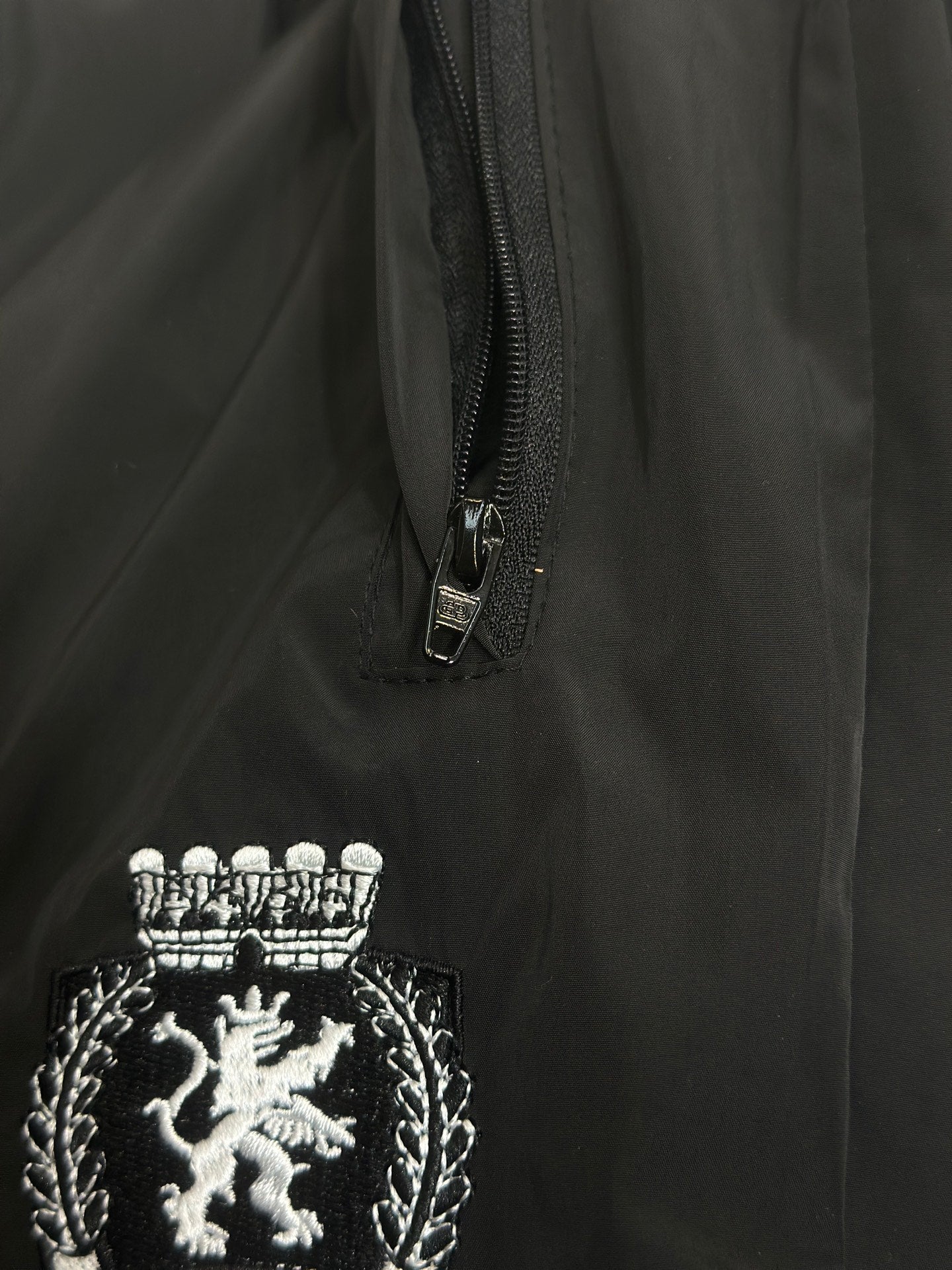 Black pants with front zipper and embroidered lion crest patch