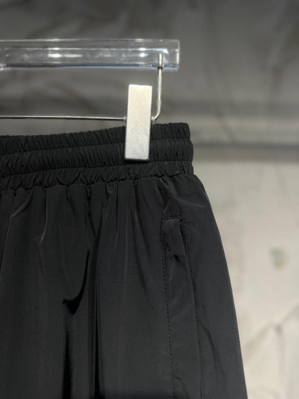 Black elastic-waist pants with front seams and side logo patch