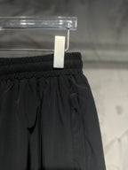 Black elastic-waist pants with front seams and side logo patch