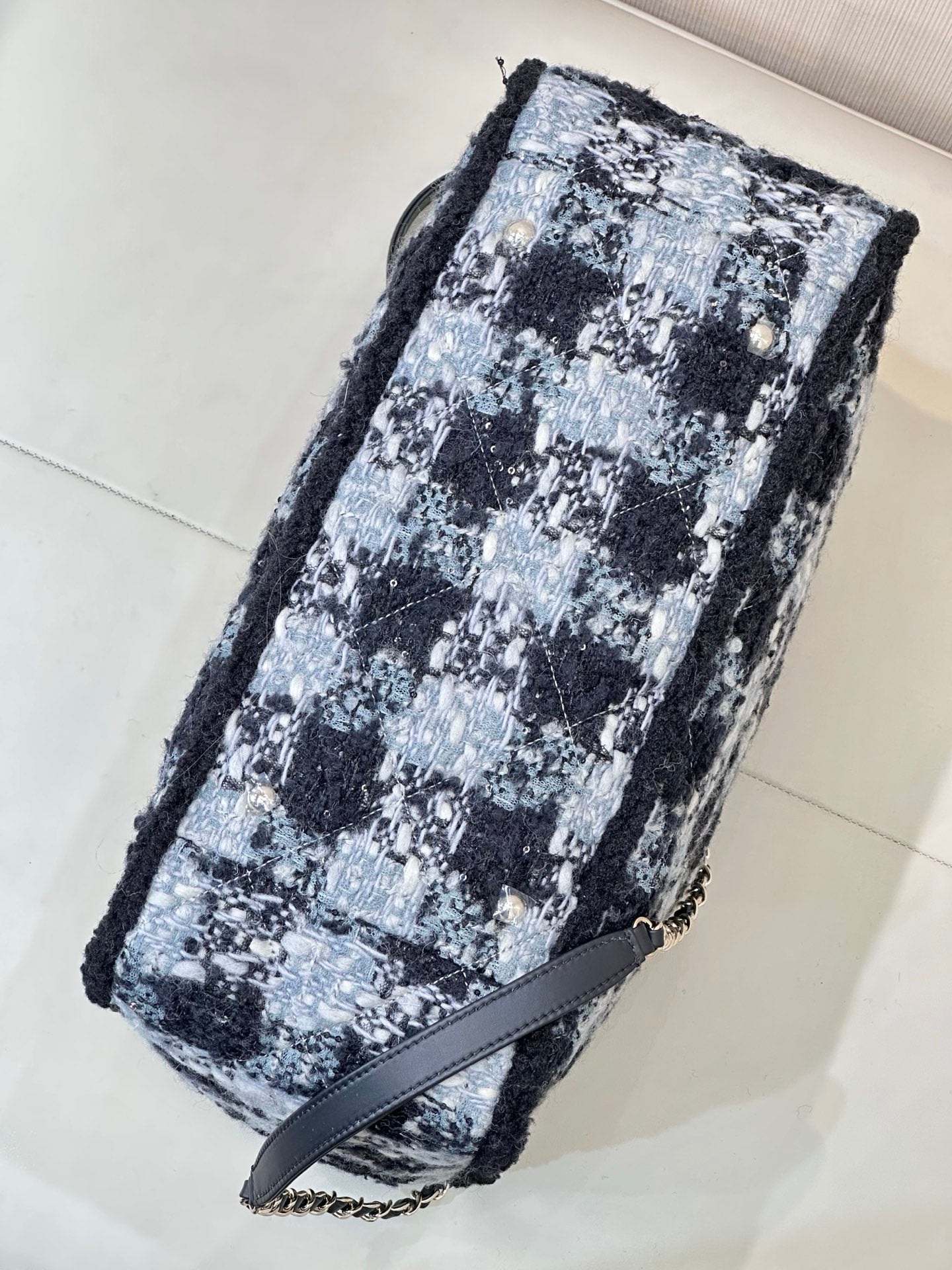 Chanel tote bag angled view in blue and black tweed with chain strap and black trim