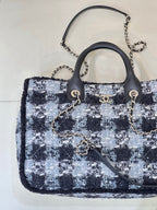 Chanel tote bag with blue/black/white tweed pattern, black handles, and chain shoulder strap