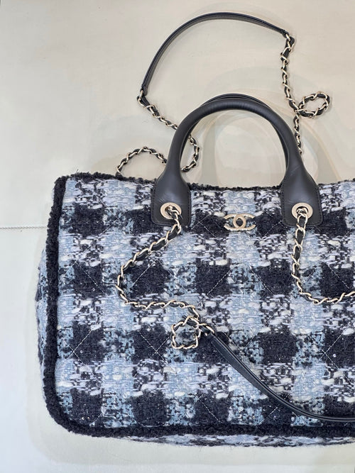 Chanel tote bag with blue/black/white tweed pattern, black handles, and chain shoulder strap
