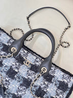 Chanel tote bag close-up: black leather handles with chain accents on blue tweed