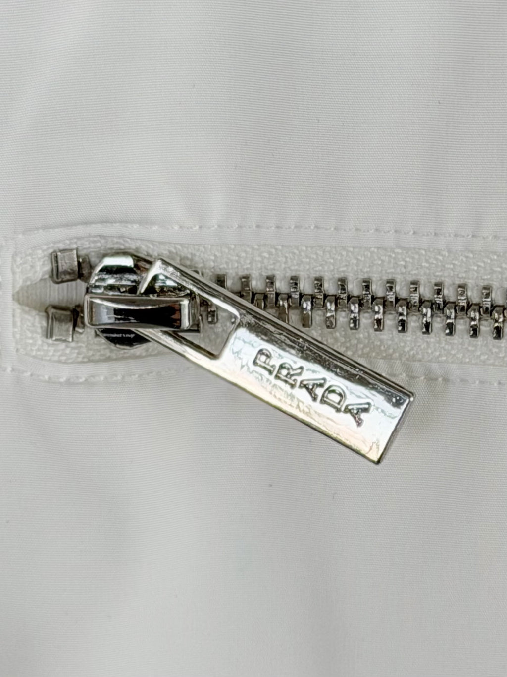 Silver metal zipper on white T-shirt with Prada Milano engraving