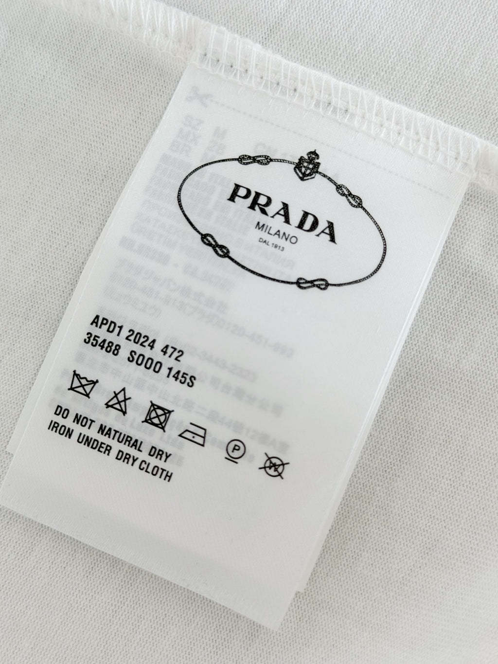 White fabric care label with Prada Milano and laundry symbols