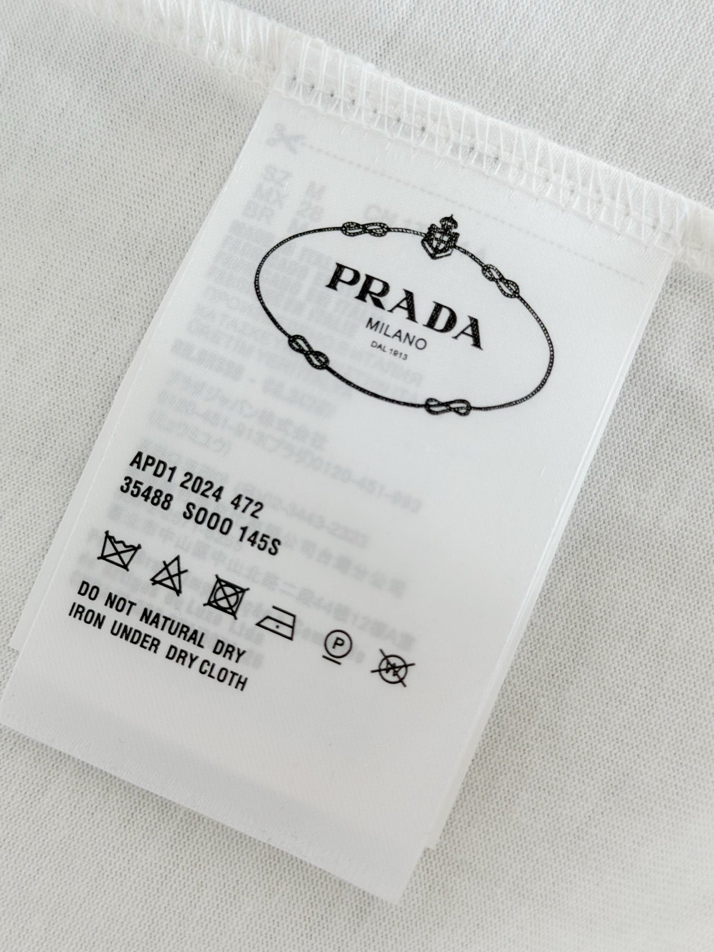 White fabric care label with Prada Milano and laundry symbols