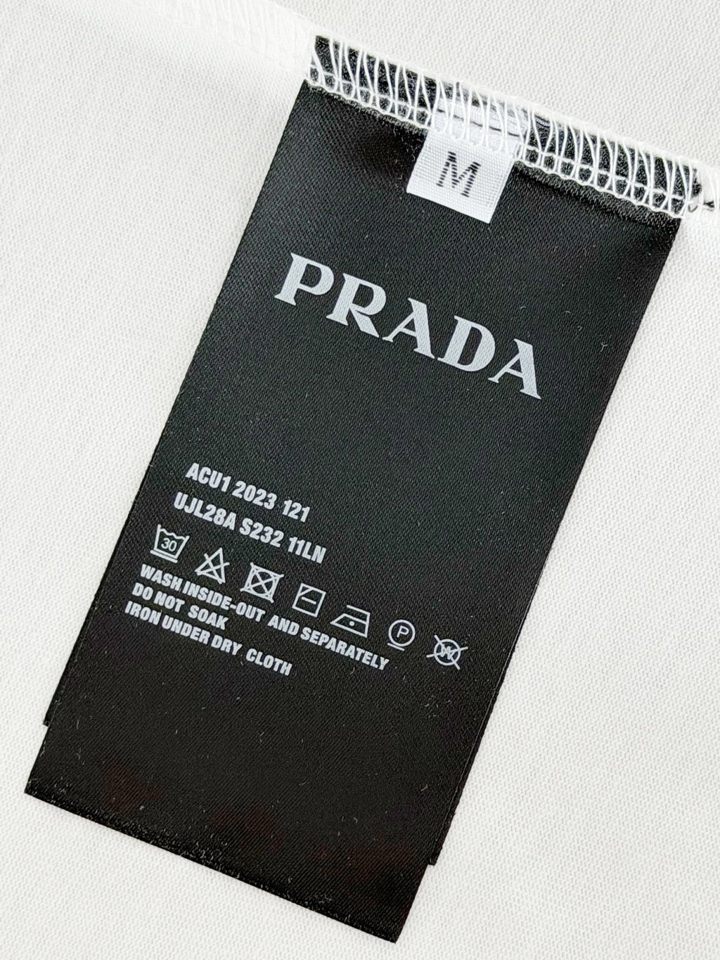 Black care label on white T-shirt fabric with Prada Milano details